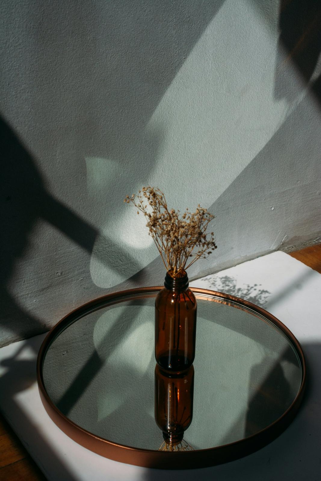 Round mirror tray with a vase in soft light